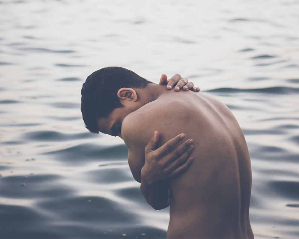 Hombre en el mar sujetándose la espalda