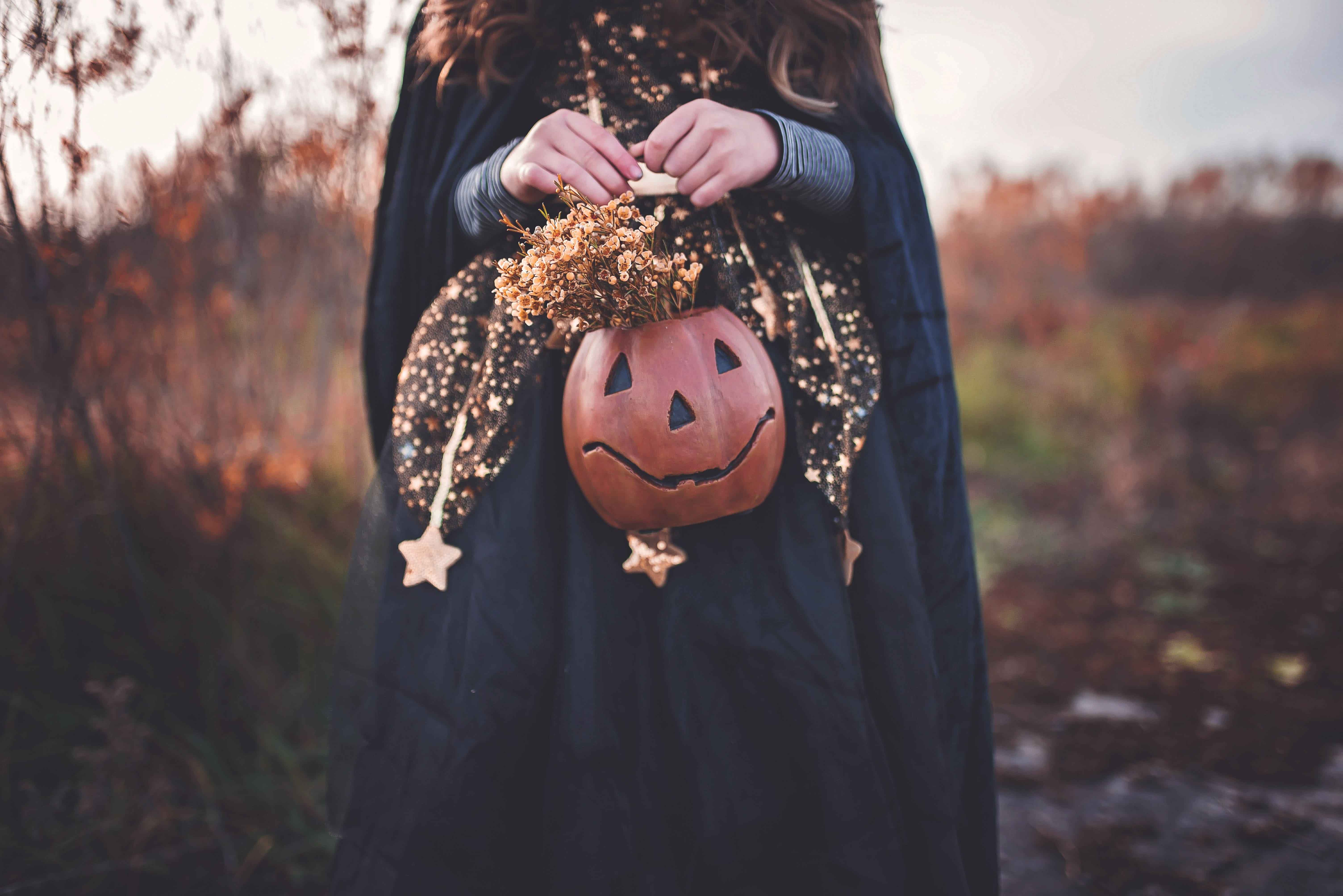 niña sujetando una calabaza de halloween